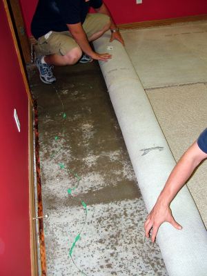 Rendon water damaged carpet being removed by two men.